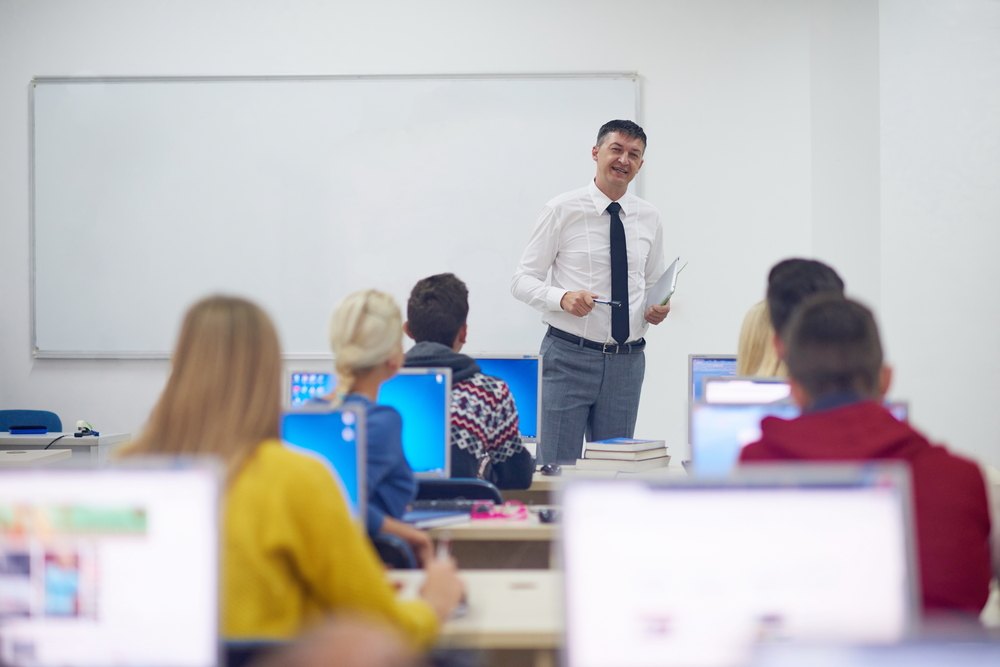 group of students with teacher in computer lab classrom learrning lessons, get help and support